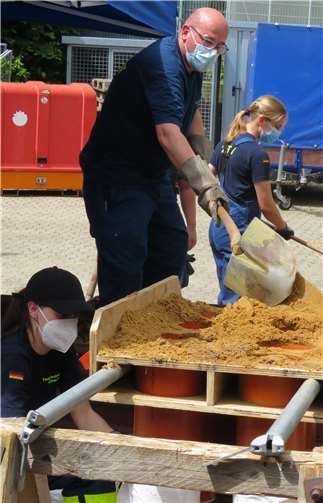 Ein THW-Helfer füllt Sand in die eigenkonstruierte Sandsackfüllapparatur.