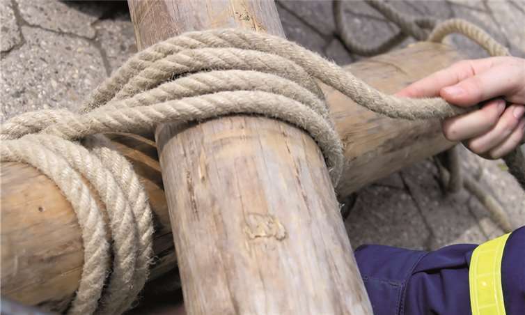 Ein THW-Helfer übt mittels einer Leine, zwei Rundhölzer zusammenzubinden.Privat