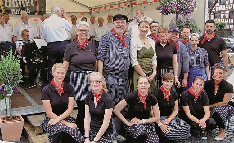 Ein großes Service-Team hatte das Ehepaar Pommer (oben links) aufgeboten, um die Gäste des Matjes-Festes zufrieden zu stellen. Mit dabei: Brunnenkönigin Anne I. Im Hintergrund auf der Bühne: Der Shanty-Chor aus Bonn. FA