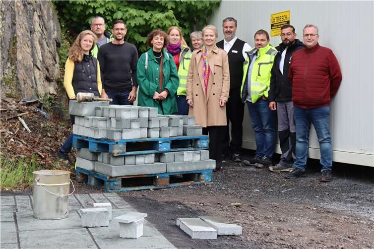 Ein grünlicher Naturstein wird künftig die Gehwege, Plätze und Parkbuchten an der neu gestalteten Bahnhofstraße in Montabaur schmücken. Am Fuße des Schlossbergs trafen sich die Projektbeteiligten, um die Musterfläche mit dem „Monte Verde“ genannten Pflaster zu sehen und zu begehen. Interessierte können die Musterfläche gegenüber der Post hinter dem Bauzaun betrachten.  Foto: VG Montabaur