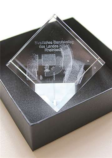 Ein in der Schule gefertigter Glaswürfel mit einer Laser-Innengravur der Silhouette des Staatlichen Berufskollegs Rheinbach.