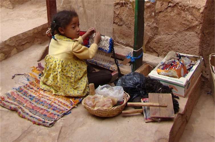 Ein kleines Mädchen knüpft einen Teppich im marokkanischen Aït-Ben-Haddou. Lizenz: cc by/3.0/de (Zouavman Le Zouave/Wikimedia Commons)