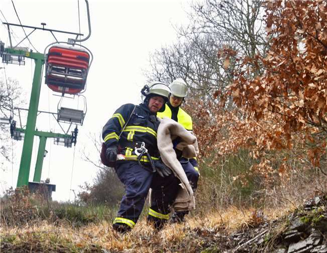 Einsatzkräfte der Feuerwehr bringen wärmende Decken,damit sich die frierenden Geborgenen darin einhüllen können.