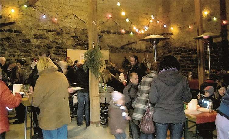Eltern, Kinder und Erzieherinnen stimmen sich gemeinsam beim Weihnachtsbasar in der Scheune auf den Advent ein.
