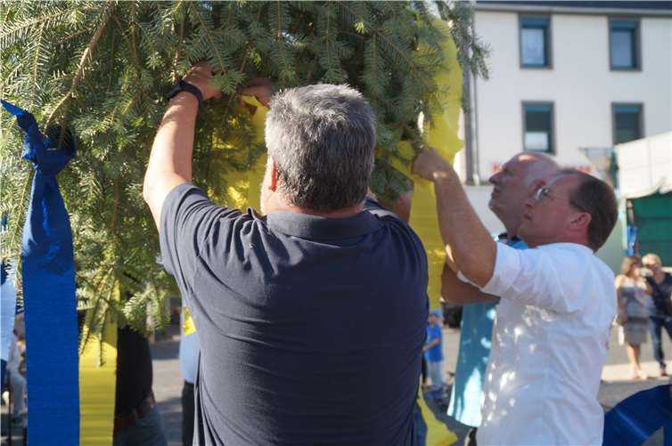 Erst Schmücken, dann Stellen: Blaues und gelbes Kreppband flattert noch eine Weile im Wind an der Spitze des Kirmesbaums.
