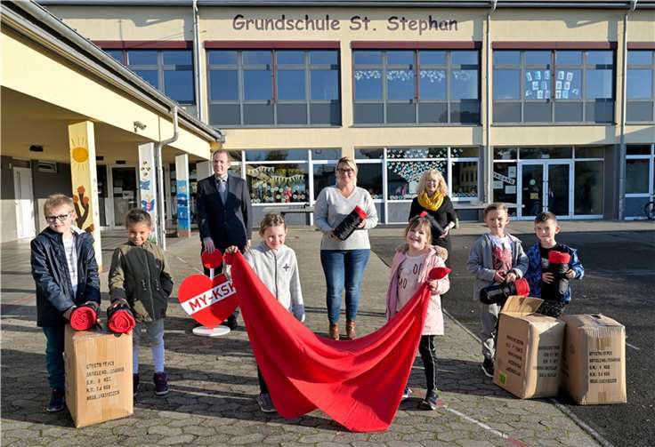 Aktion „Rote Decken für kalte Tage - es geht weiter!“ Erstklässler der Grundschule St. Stephan (vorne) freuen sich gemeinsam mit Schulleiterin Angelika Baulig (mitte hinten), KSK- Filialleiter Christian Schwarz (hinten links) und KSK-Jugendmarktbetreuerin Michaela Schneider (hinten rechts).Foto: KSK Mayen/ Ralph Künzel