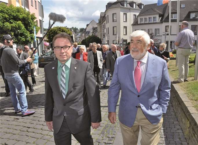 Es ist 11.30 Uhr. Mario Adorf und OB Wolfgang Treis schlendern zur Enthüllung des Burgweg Schildes. in Begleitung vieler Fans und Offiziellen. -BS-