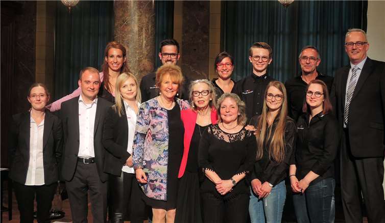 Eva Keil-Becker (hintere Reihe links außen) und Brigitte Hilgert-Becker (vorne, 4. v. li.) als Geschäftsführer von Becker Hörakustik zusammen mit dem Filialleiter von Becker Hörakustik in Bad Ems, Robert Dittrich (vorne, 2. v. li.), dem Geschäftsführer von Brillen Becker, Jörg Linnebacher (re.), der Moderatorin Annegret Ritzel (vorne 5. v. li.) sowie den Mitarbeiter-Teams.BSB