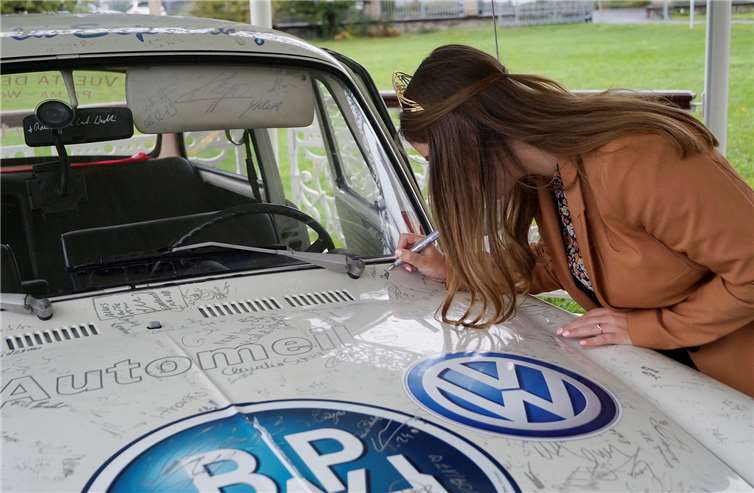 Eva Lanzerath unterschreibt den VW, der demächst in einer Charity-Auktion versteigert wird.