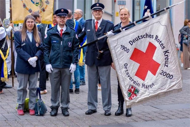 Fahnenabordnungen beim Festumzug des 75. Stein- und Burgfest in Mayen. Im Bild zu sehen die Fahnenabordnung des DRK OV Mayen mit Bernd Müller (Fahnenträger, stellv. Vorsitzender und langjähriger Zugführer), Margret Müller (li. im Bild), daneben Dominik Delfing, und rechts im Bild über der Fahne Manuela Höhne.