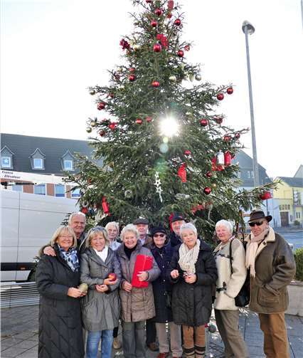 Familie Warzel mit Freunden am geschmückten Weihnachtsbaum. Eich