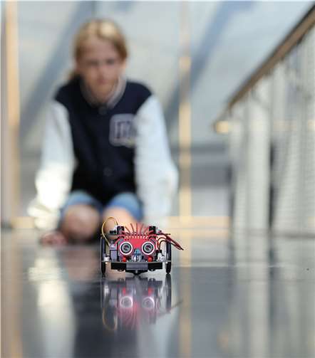 Ferienkursteilnehmerin Lynn programmiert und bestaunt den Callibot-Roboter. Foto: Hochschule Koblenz/Susanne Dröppelmann