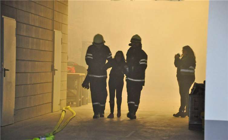 Feuerwehrmänner führen Person aus der Halle.