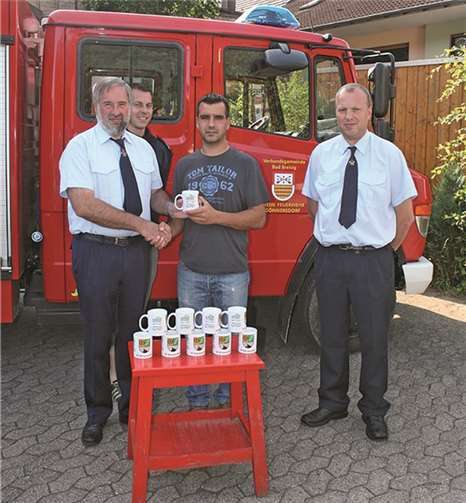 Firmeninhaber Dennis Schütz überreicht Wehrführer Manfred Mallmann im Beisein seines Stellvertreters Uwe Knoff und dem Stellvertretenden Wehrleiter Ronny Zilligen die neuen Kaffepötte.WER