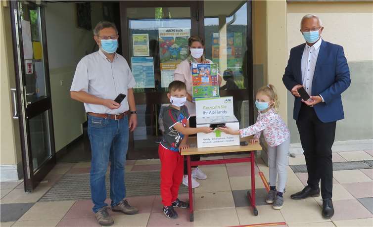 Foto (v.l.n.r.): Schulleiter Michael Barde mit Schülern der 2. Klasse der Grundschule Melsbach, die Landrat Achim Hallerbach und der Vertreterin der Stabsstelle für Energie, Klima und Umwelt, Gaby Schäfer die volle Handysammelbox präsentieren .Foto:Quelle: Kreisverwaltung