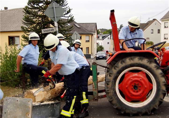 Frank Sellner von der Feuerwehr sägt den Kirmesbaum zurecht, damit er nicht in Schieflage gerät.