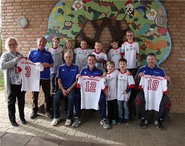 Frau Doebel, die Rektorin der Leimersdorfer Grundschule, nimmt mit der Schulmannschaft freudig den neuen Trikotsatz entgegen. privat