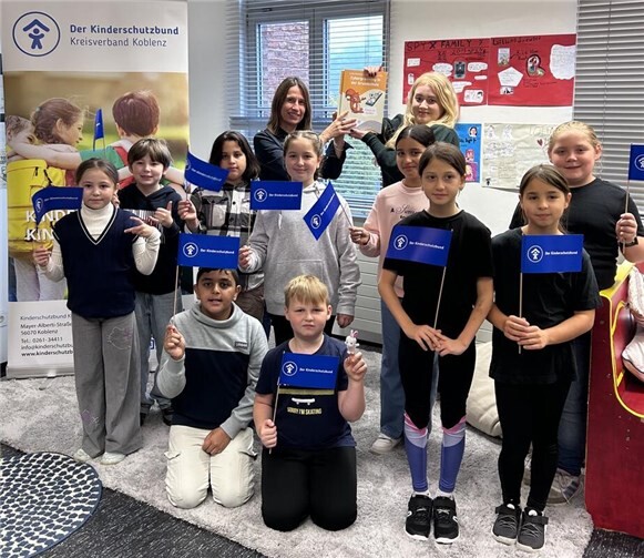 Flizzy, das Eichhörnchen, schützt Kinder vor Cybergrooming  Frau Richert vom Kinderschutzbund Koblenz übergibt die Cybergrooming Broschüren an Schülerinnen und Schüler der Willi-Graf-Grundschule Neuendorf. hinten v.l.: Melanie Bollinger-Wey (Konrektorin), Annette Richert (Fachkraft DKSB Koblenz). Foto: Kinderschutzbund Koblenz