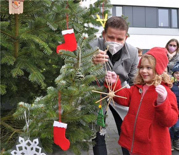 Freudestrahlend schmücken die Kinder der Kita Villa Regenborgen und Bürgermeister Holger Jung den Weihnachtsbaum vor dem Rathaus.Foto: Stadt Meckenheim