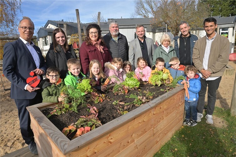 Freuen sich im Rahmen des Kreisprojektes „Mehr als nur grün“ über des neue Hochbeet des städtischen Kindergartens St. Genovefa in Mendig. Von links: Jochen Siewert als stv. Vorstandsmitglied der KSK Mayen, Nina Heckenbach als KSK- Jugendmarktbetreuerin, Alexandra Menge von Presto Humus GmbH, Achim Grün als Bürgermeister, Landrat Marko Boos, Erzieherin Sabine Schmitt, Werner Schneider von KommAktiv GmbH und Raymundo König-Queng als Leiter des städtischen Kindergartens St. Genovefa in Mendig im Beisein einiger Obrmendiger Kindergartenkinder. Foto: KSK Mayen/ Ralph Künzel