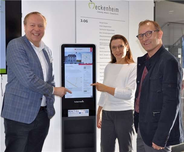 Freuen sich über das neue digitale Informationsangebot wie hier im Rathaus-Foyer, von links: Markus Bergmann vom City-Hotel sowie Sonja Crämer und Dirk Schwindenhammer von der Wirtschaftsförderung. Foto: Stadt Meckenheim