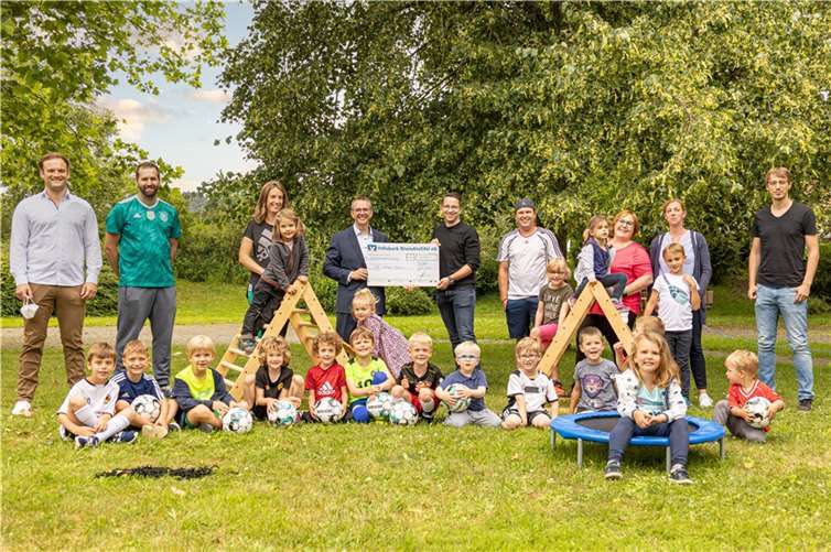 Freuen sich über die 750-Euro-Spende der Volksbank RheinAhrEifel eG an den VfR Waldorf 1920 e.V.: Jörg Girolstein, Private-Banking-Betreuer bei der Volksbank aus Waldorf (hintere Reihe, 4.v.l.) und Michael Zepp, 2. Vorsitzender des Vereins (hintere Reihe, 5.v.l.) sowie die Vereinskinder plus Eltern. Foto: Michael Schmitz