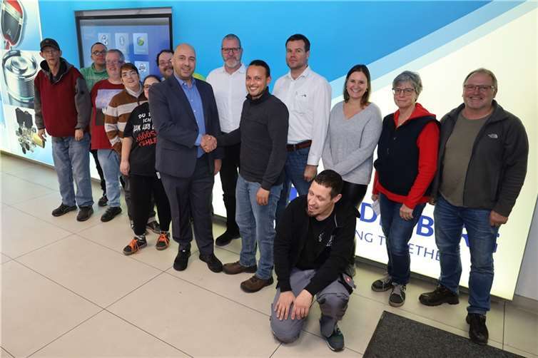 Freuen sich über die Zusammenarbeit: Tobias Chomsé (Geschäftsführer der Integral Accumulatoren, Mitglied der Freudenberg Gruppe) und Abteilungsleiter Ruben Scek Hassan sowie Mitglieder der Außenarbeitsgruppe und Mitarbeitende von Freudenberg.  Foto: Thomas Hoffmann / Caritas Werkstätten