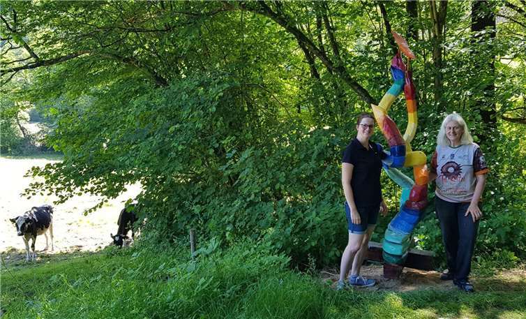 Fröhlich bunt leuchtet der „Meilenstein“ an seinem Standort hoch über dem Gelbachtal. Die Skulptur von Simone Levy (l.) wurde auf Anregung von Ortsvorsteherin Janine Best (r.) in Reckenthal aufgestellt und markiert dort den neuen Abzweig des Skulpturenwegs. Foto: Stadt Montabaur / Christian Best