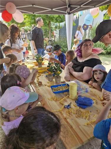 Fröhliches Sommerfest in der Kita „Sonnengarten“: Kinder, Erzieherinnen und Gäste beim kreativen Nudelketten-Stecken – Spaß und Gemeinschaft pur! Foto: Stadt Meckenheim