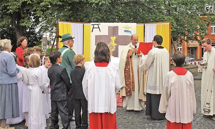 Fürbitten und Lesungen während der Fronleichnamsprozession in Rheinbach. Hier halten die Gläubigen am Außenaltar Prümer Wall inne.Stein