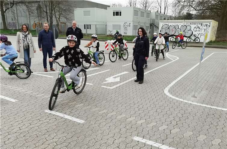 GEWI-Geschäftsführerin Sofia Lunnebach, Bürgermeister Andreas Geron, Maik Hellmich und Monika Schäfer von der PI Remagen (v.l.) mit den Kindern der 4a der Regenbogenschule auf dem wiedereröffneten Verkehrsübungsplatz. Foto: -BL-