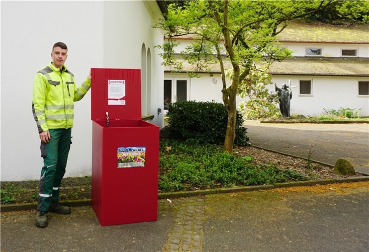 Gärtner Leon Rommersbach öffnet den Deckel einer roten Retterbox für verblühte Blumenzwiebeln. Sie stehen auf dem Hauptfriedhof und den Bezirksfriedhöfen Metternich und Asterstein bereit.  Foto: Stadt Koblenz/Verena Groß