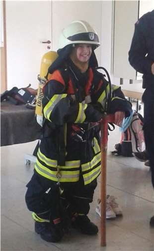 Ganz schön schwer, so eine Persönliche Schutzausrüstung eines Feuerwehrmannes. Das Gewicht der Atemschutzausrüstung kann der Schüler kaum stemmen.