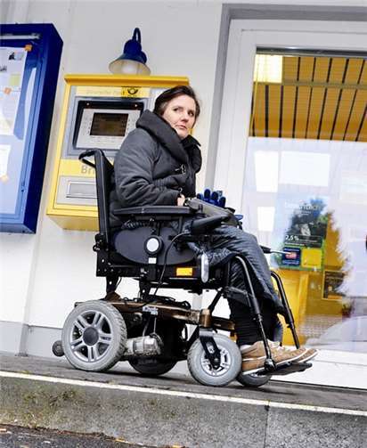 Gefährlich hoch ist die Stufe am schmalen Gehweh vor der Post: Gabi Gummersbach fährt sehr vorsichtig und muss zum abgeflachten Stück einen Umweg machen.