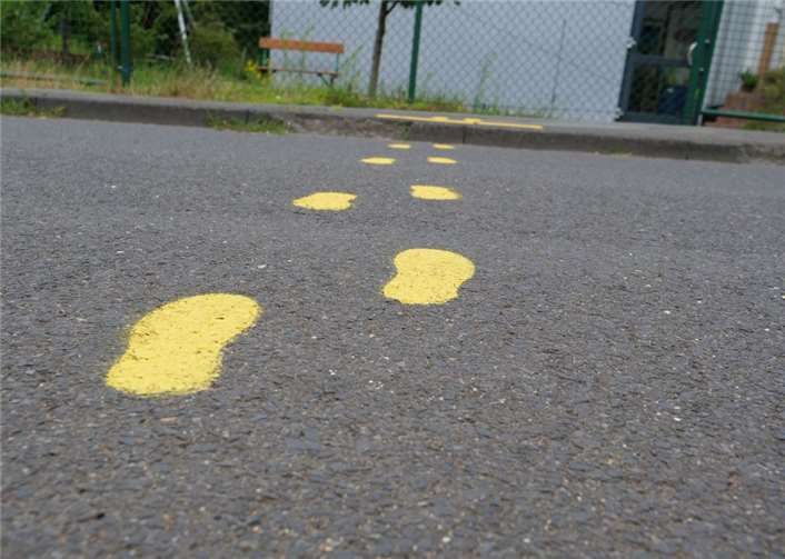 Gelbe Füße zeigen Kindern sichere Wege im Straßenverkehr auf.