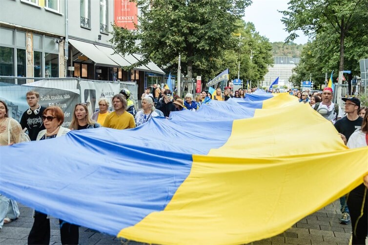Gemeinsam durch die Innenstadt: Teilnehmerinnen und Teilnehmer tragen die 50 Meter lange ukrainische Flagge durch die Koblenzer Schlossstraße.