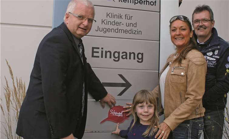 Gemeinsam mit Minka Bojara und Bernhard Dostert (rechts) vom Familienbündnis und der fünfjährigen Amelie bringt Karl Ehrmann, Kaufmännischer Direktor des Kemperhofs, den Aufkleber der Aktion „Schängel in Sicherheit“ im Eingangsbereich der Klinik für Kinder- und Jugendmedizin an.privat