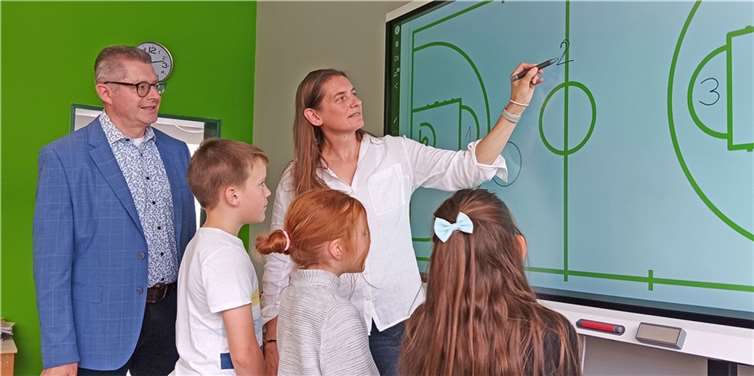Gemeinsam mit Schulkindern ließ sich Schuldezernent und Erster Beigeordnete Hans Dieter Wirtz von der stellvertretenden Schulleiterin Silke Brämm die Funktionsweise des Smartboards erklären. Foto: Stadt Meckenheim