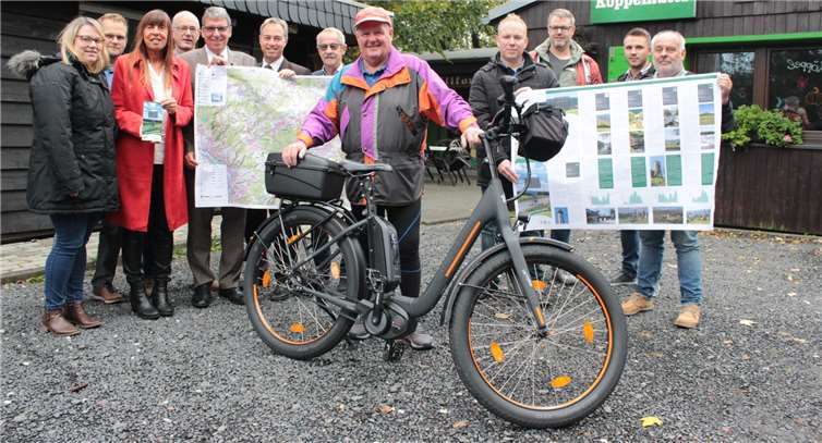Gemeinsam stellen die Verantwortlichen der beteiligten Kommunen die neue Radkarte vor (v.l.n.r.) Jasmin Weber (Ransbach-Baumbach), Christoph Eul (Fa. Mantomedia), Karin Maas (Montabaur), Markus Ströher (Höhr-Grenzhausen), Beigeordneter Andree Stein (Montabaur), Bürgermeister Michael Merz (Ransbach-Baumbach), Beigeordneter Reinhard Heuser (Höhr-Grenzhausen), Mark Goldhausen (Wirges), Markus Meuer (Wirges) sowie Harald Schnug (Höhr-Grenzhausen) und Rico Brenner (Höhr-Grenzhausen). Im Vordergrund ein Radfahrer, der sich über das erste Exemplar der Karte freute.Foto: Sabine Rödder