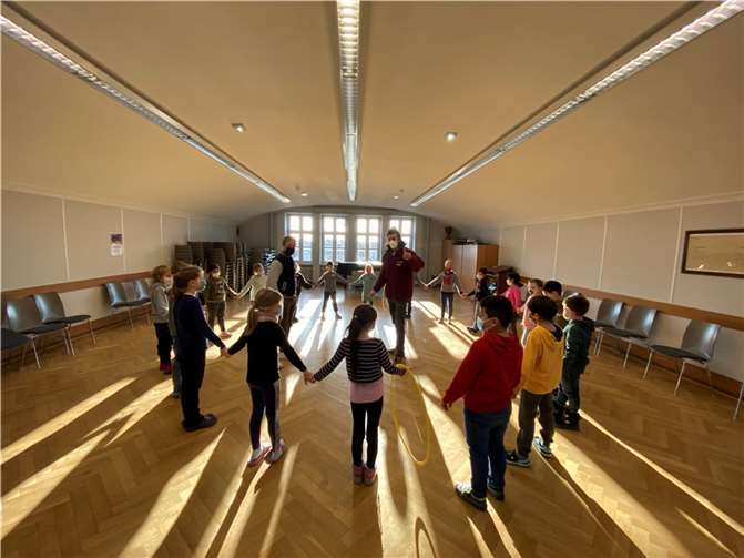 Gemeinsam zum Ziel – Die Kinder halten sich an den Händen und versuchen einen Reifen eine Runde lang kreisen zu lassen. Nur gemeinsam können sie es schaffen. Die Couches Jens Houtrouw und Viktor Drewes der Rheinflanke stehen in der Mitte des Kreises und beobachten die Kinder, um ihnen später wertvolle Tipps zu geben.Foto: privat