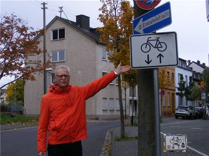 Georg Wilmers vom ADFC präsentiert das von Aufklebern befreite Schild, das jetzt wieder klar und deutlich erkennbar ist. Rechts unten im Bild das Schild vor der Reinigung.
