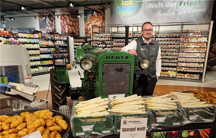 Neuer, schöner und moderner Geschäftsführer Alexander Kreuzberg am eye-catcher im Eingangsbereich des neu gestalteten EDEKA-Centers, einem alten, aber überholten und fahrbereiten Deutz-Traktor.