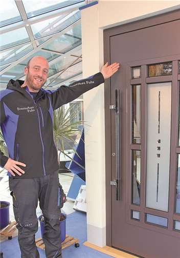 Geschäftsführer Bastian Fuhs vor einer der gut isolierten Aluminiumhaustüren mit Sicherheitsglas und -schloss im Showroom.BÜN