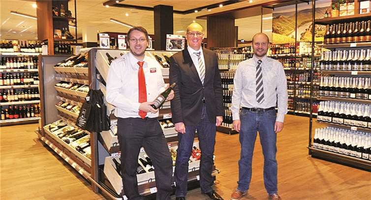 Geschäftsführer Björn und Jörg Hundertmark (v.re.) mit Marktleiter Michael Gräf in der ebenso rustikal wie spektakulär gestalteten und ausgestatteten Weinabteilung. privat