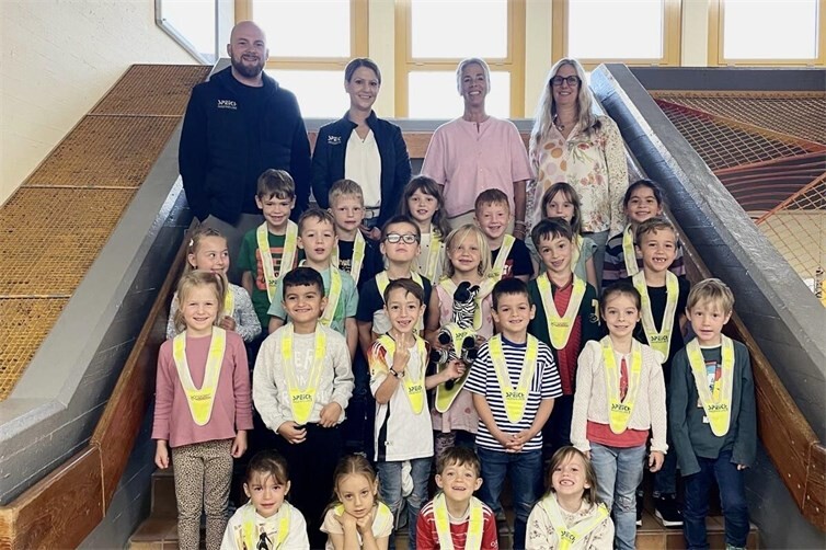 Geschäftsführerin Sara Bellinghausen und KfZ-Verständiger Alexander Wirtz überreichen den Erstklässlern der Grundschule Linz am Rhein reflektierende Sicherheitsdreiecke. Die Spende des Ingenieurbüros Speich und der Firma Krüger Werbetechnik soll zu mehr Sicherheit durch Sichtbarkeit auf dem Schulweg beitragen. 