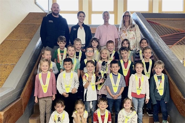 Geschäftsführerin Sara Bellinghausen und KfZ-Verständiger Alexander Wirtz überreichen den Erstklässlern der Grundschule Linz am Rhein reflektierende Sicherheitsdreiecke. Die Spende des Ingenieurbüros Speich und der Firma Krüger Werbetechnik soll zu mehr Sicherheit durch Sichtbarkeit auf dem Schulweg beitragen.
