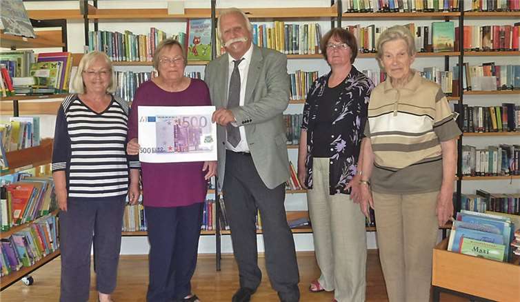 Geschäftsstellenleiter Leonard Hüllen überreicht den Scheck an das Bücherei-Team. privat
