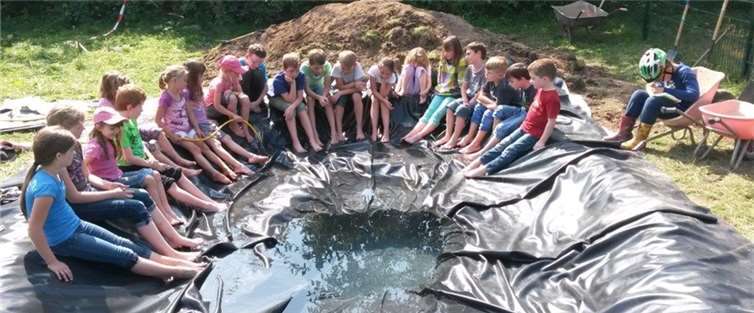 Gespannt beobachten die Kinder das Einlaufen des Wassers in ihren eigenen Gartenteich.  Privat
