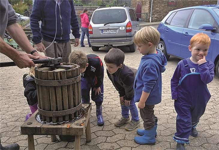 Gespannt schauen die Kleinen, wann der gepresste Saft ihrer gesammelten Äpfel aus der Presse läuft. privat