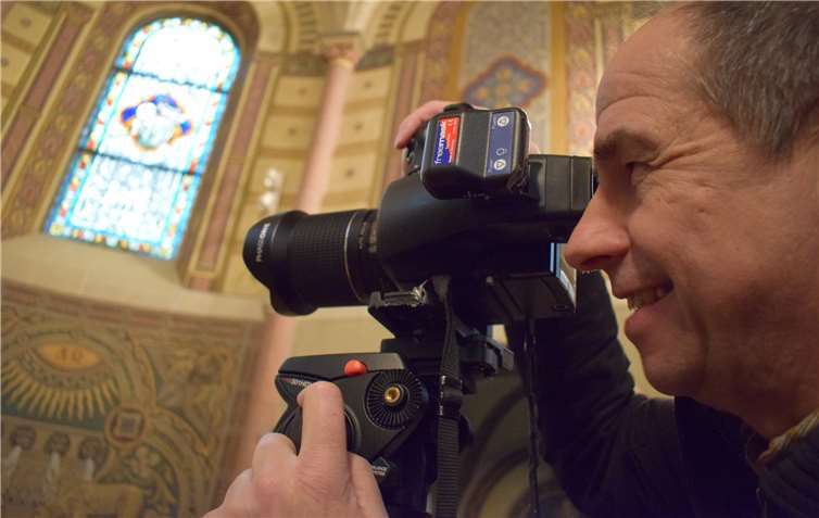 Gisbert Sacher nimmt die dekorierte Wand im Altarraum der Kaiser-Wilhelm-Kirche in den Focus, um dem Schadensumfang auf die Spur zu kommen. Fotos: Dekanat Nassauer Land